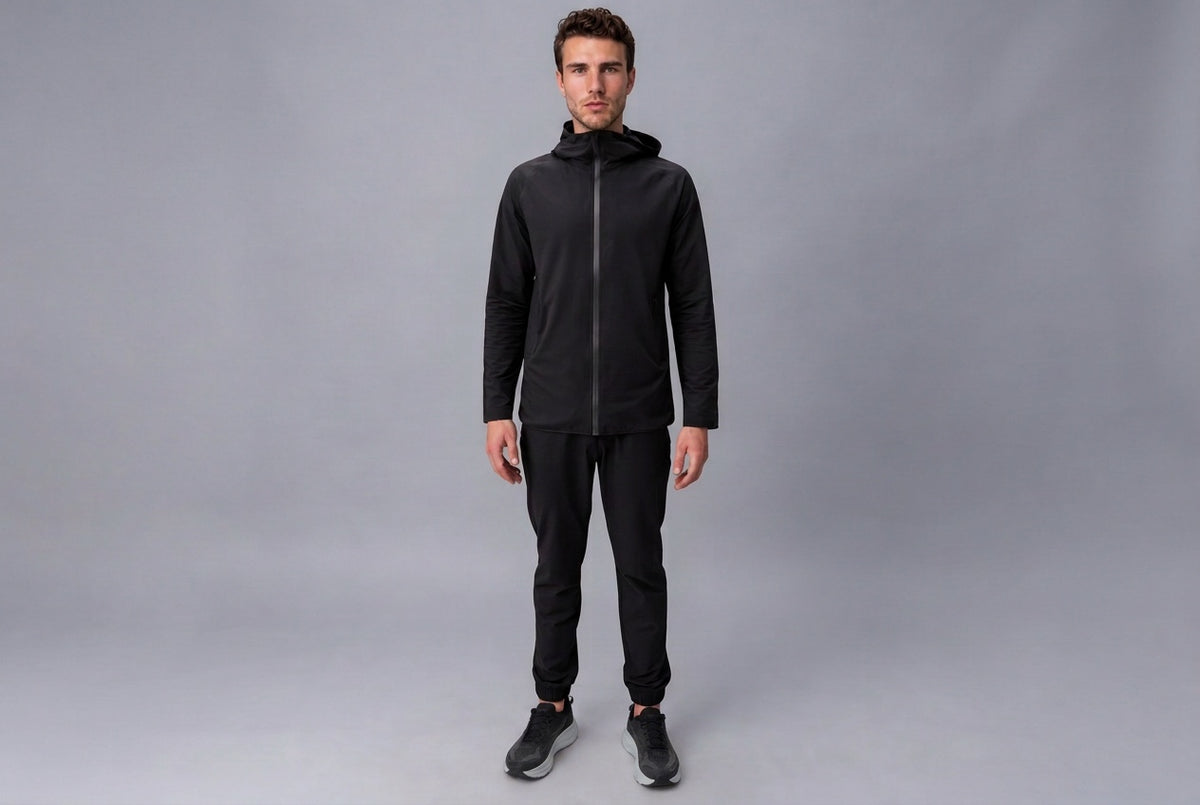 Model wearing the black Antero tracksuit against a grey studio backdrop